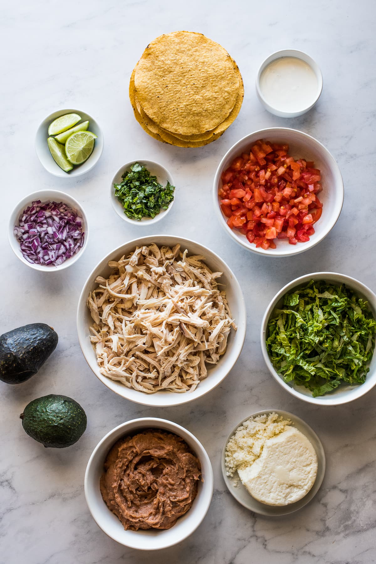 Ingredients in chicken tostadas in various bowls.