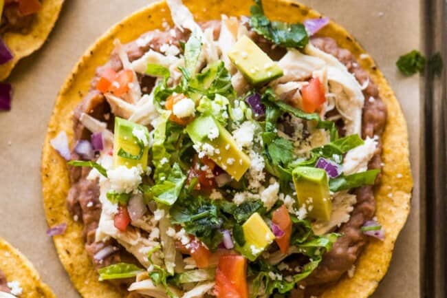 Chicken Tostadas topped with cilantro, cheese, and avocado.