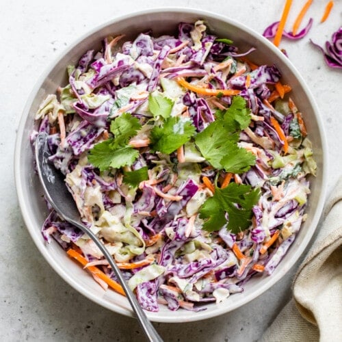 Fish taco slaw in a bowl topped with cilantro leaves.