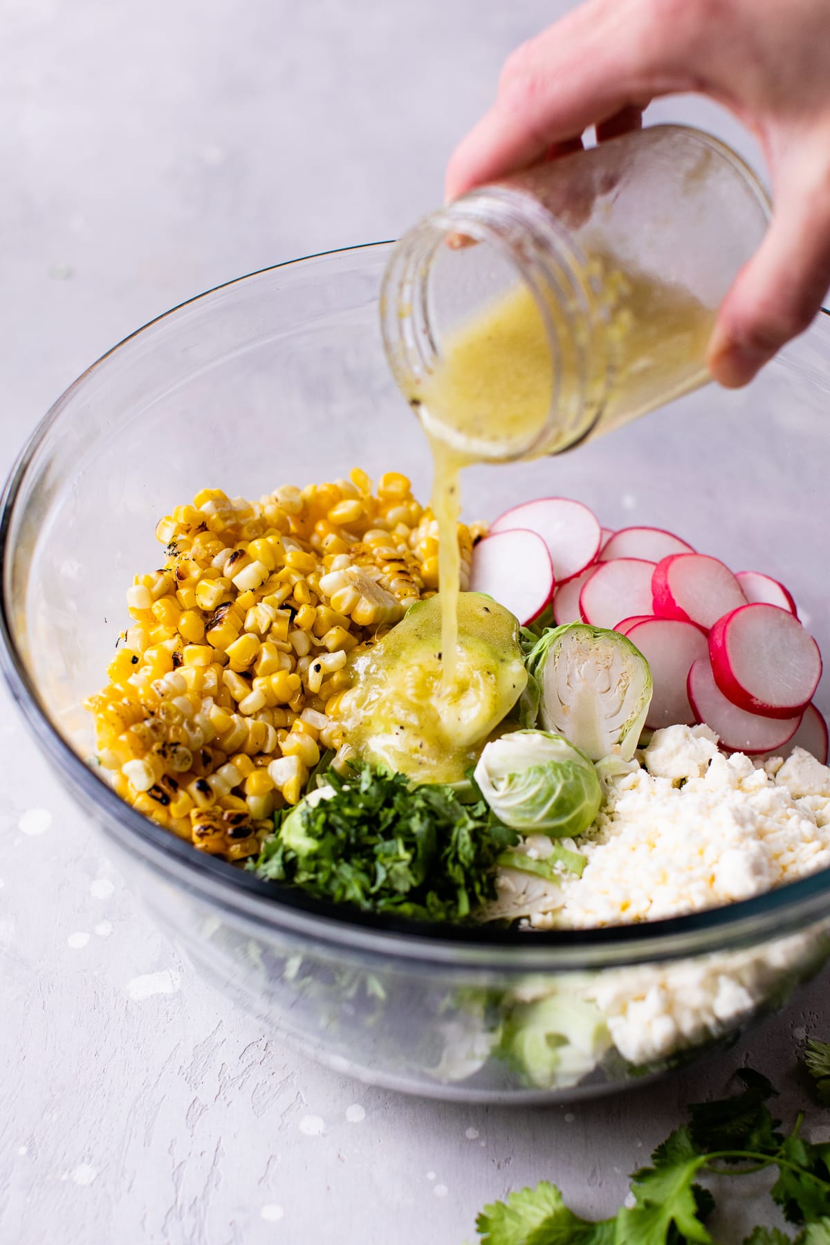 Dressing being poured over ingredients in bowl.