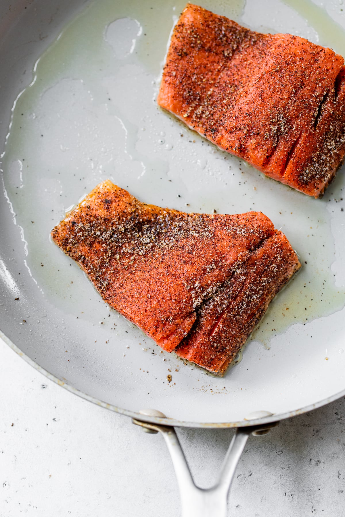 Salmon fillets cooking on a skillet.