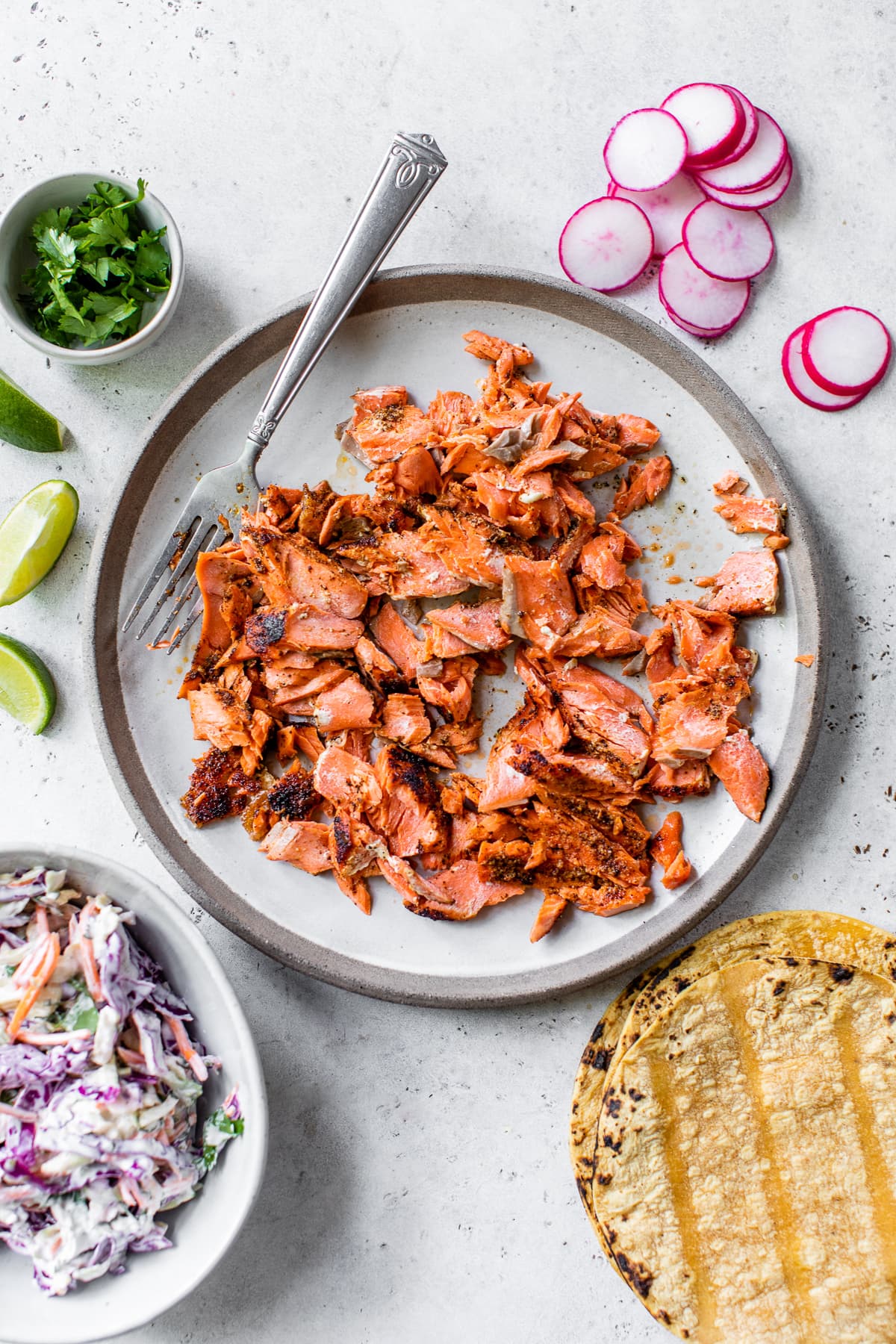 Flaked salmon pieces on a plate ready to be made into salmon fish tacos.