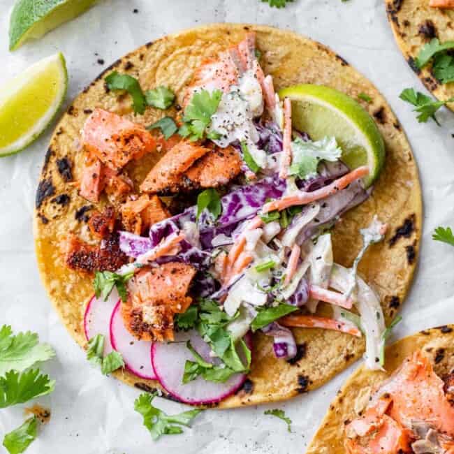 Tacos de salmón cubiertos con una ensalada cremosa y cilantro fresco.