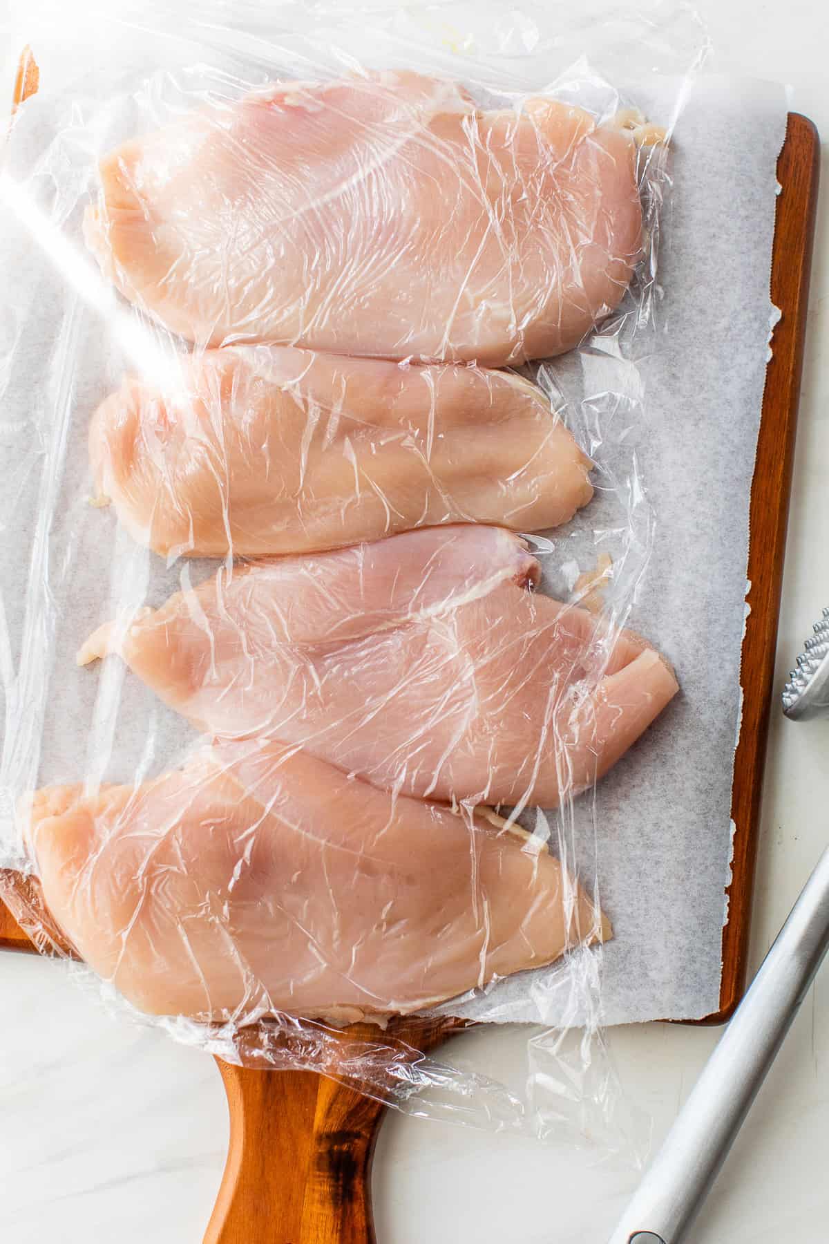 Chicken breast pounded thinly on a cutting board.