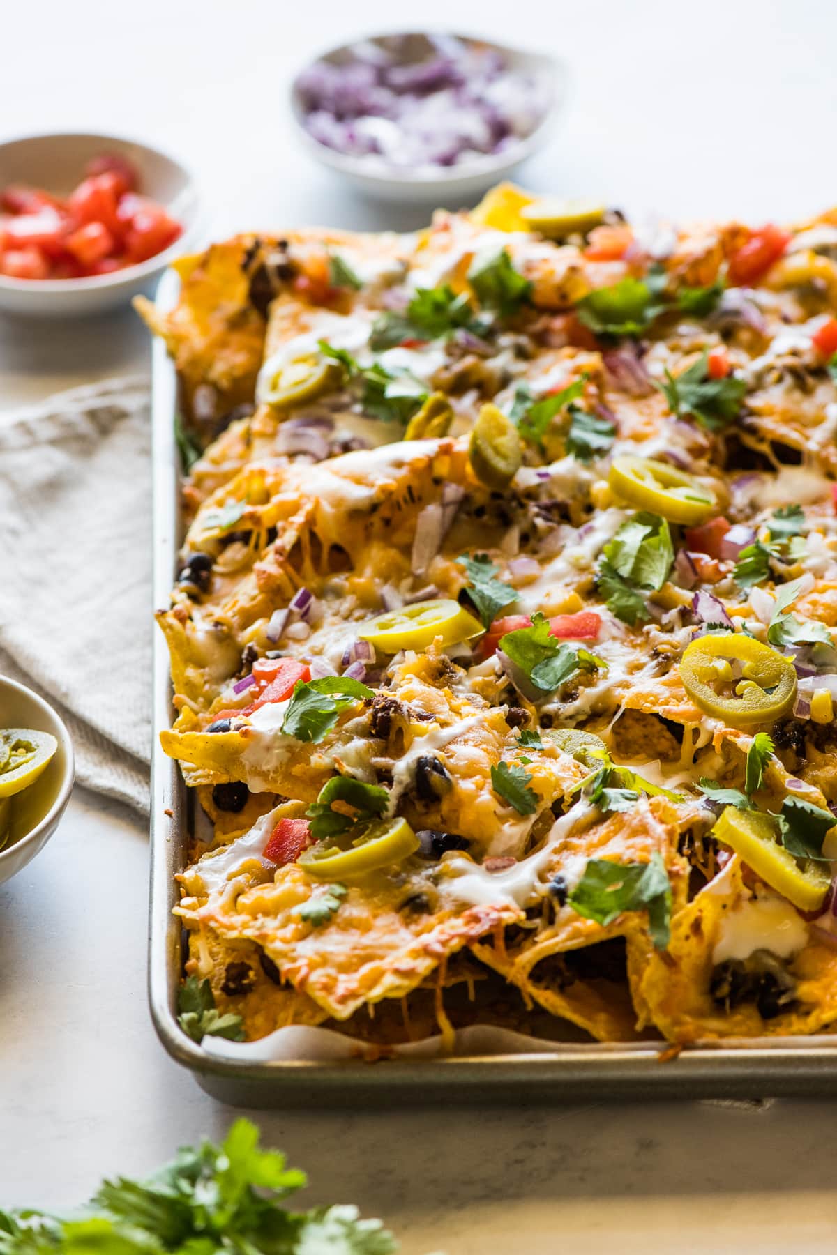 Loaded sheet pan nachos topped with lots of Mexican toppings.