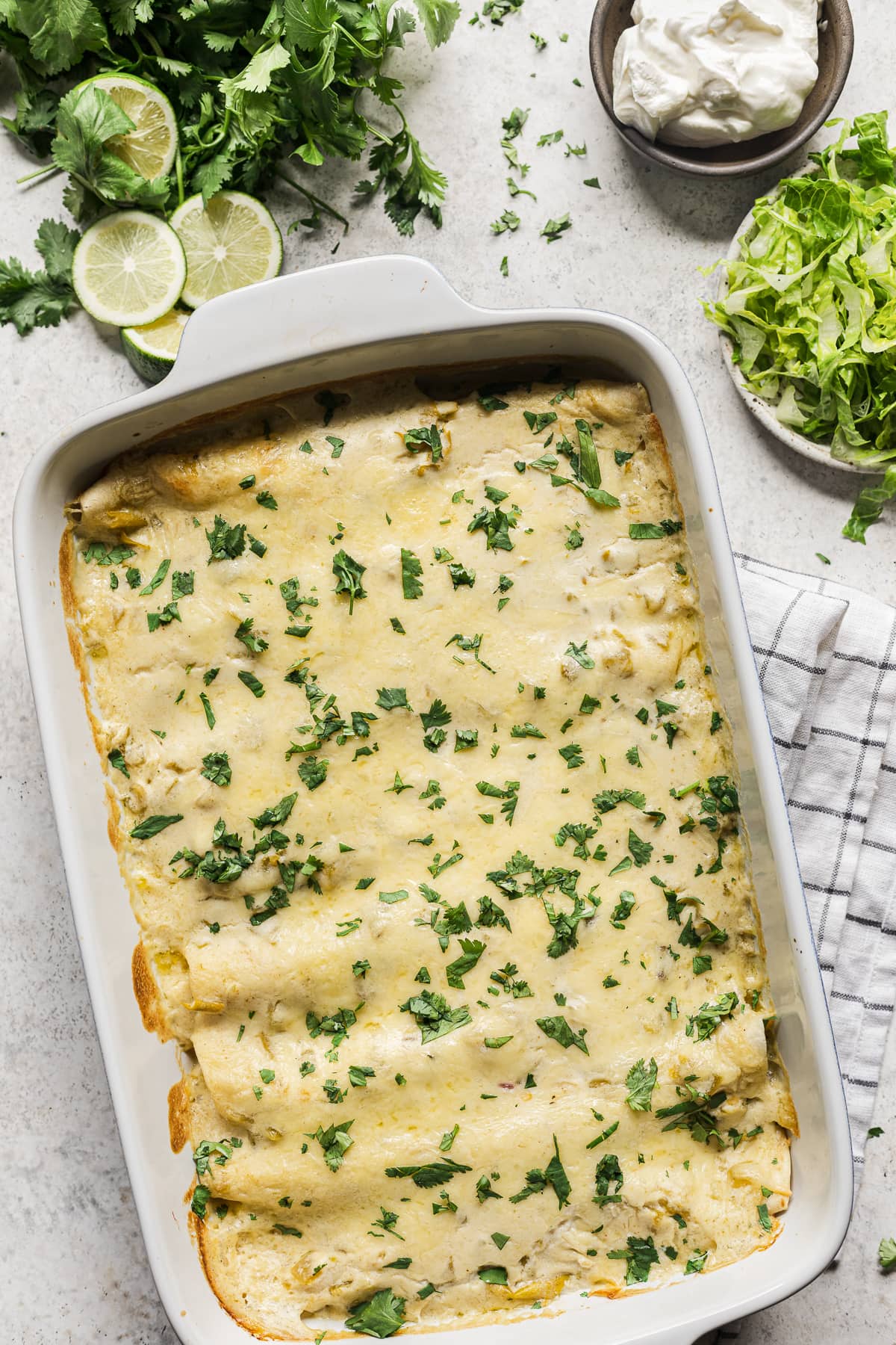 A baking dish full of white chicken enchiladas ready to be served and eaten.