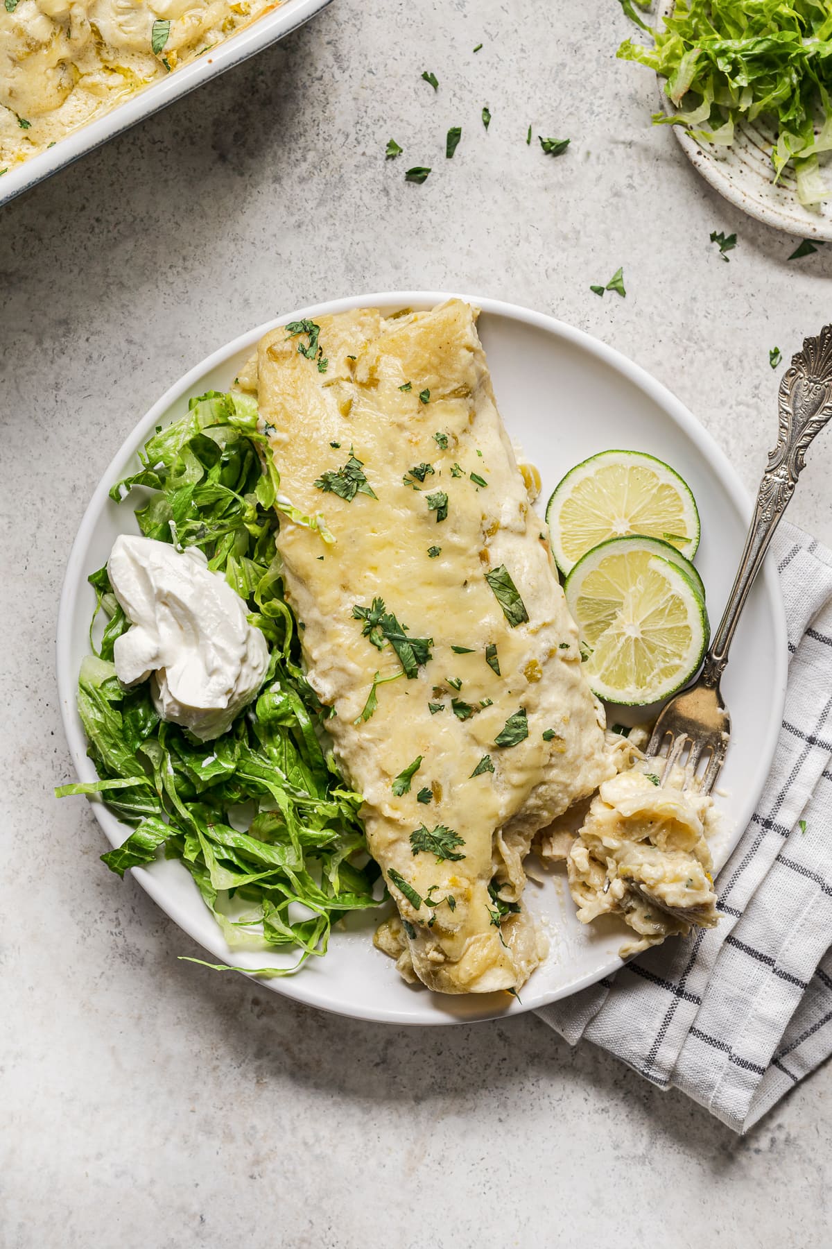 White Chicken Enchilada on a plate with shredded lettuce and sour cream.