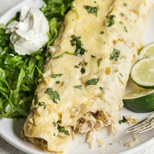 White chicken enchiladas topped with cilantro on a plate.