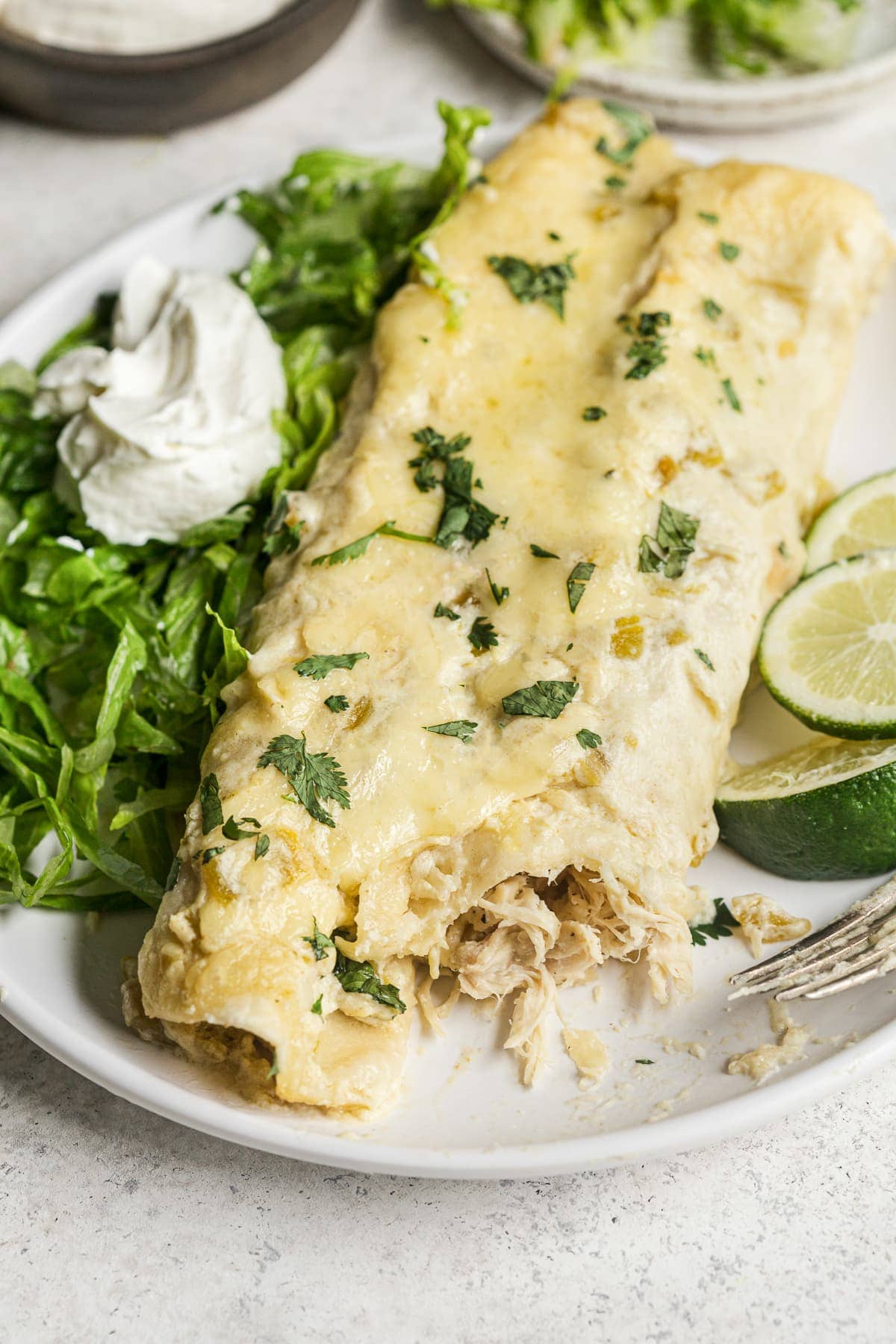 White chicken enchiladas topped with cilantro on a plate.