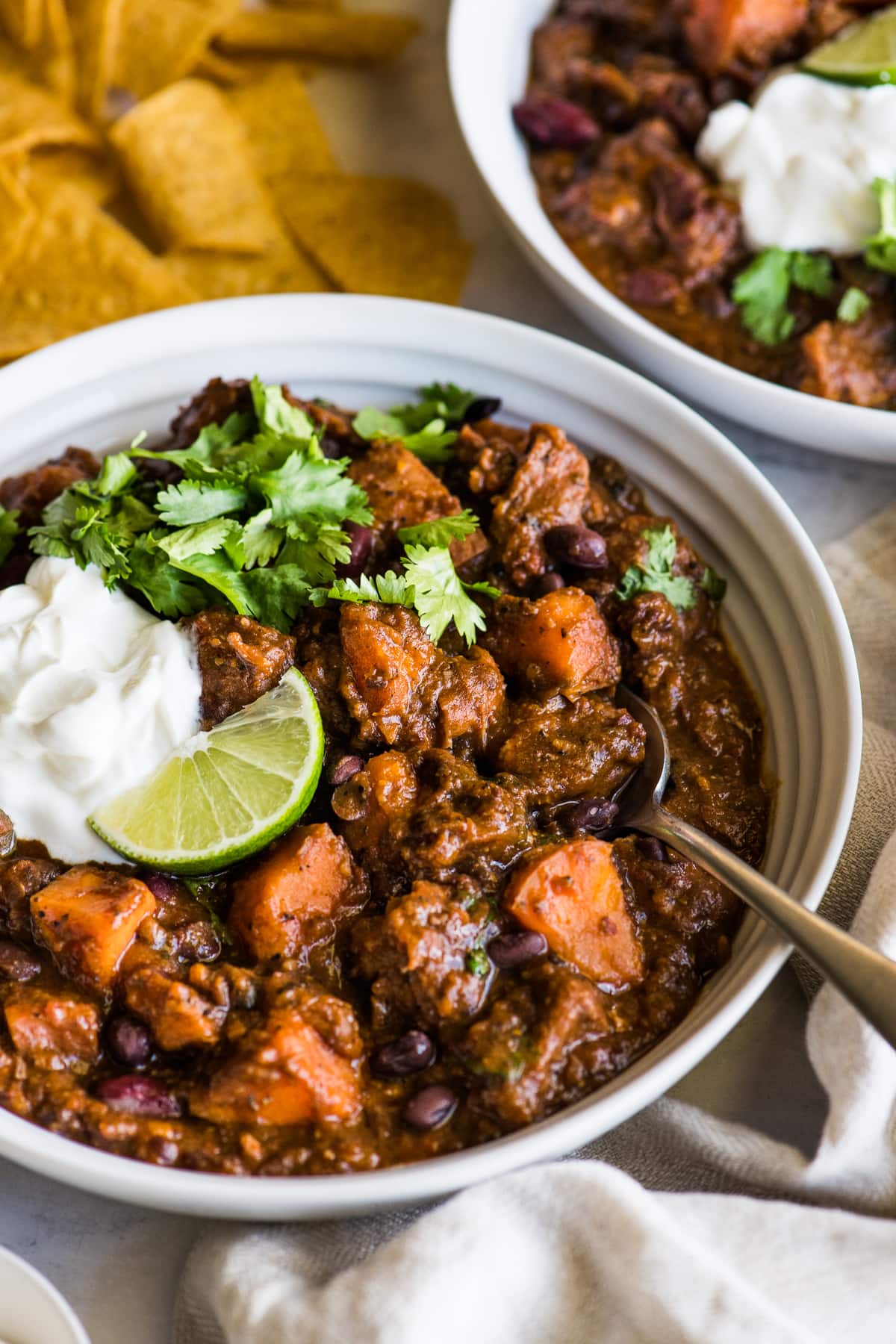 Chipotle Sweet Potato Pork Chili topped with sour cream, cilantro, and a lime wedge.