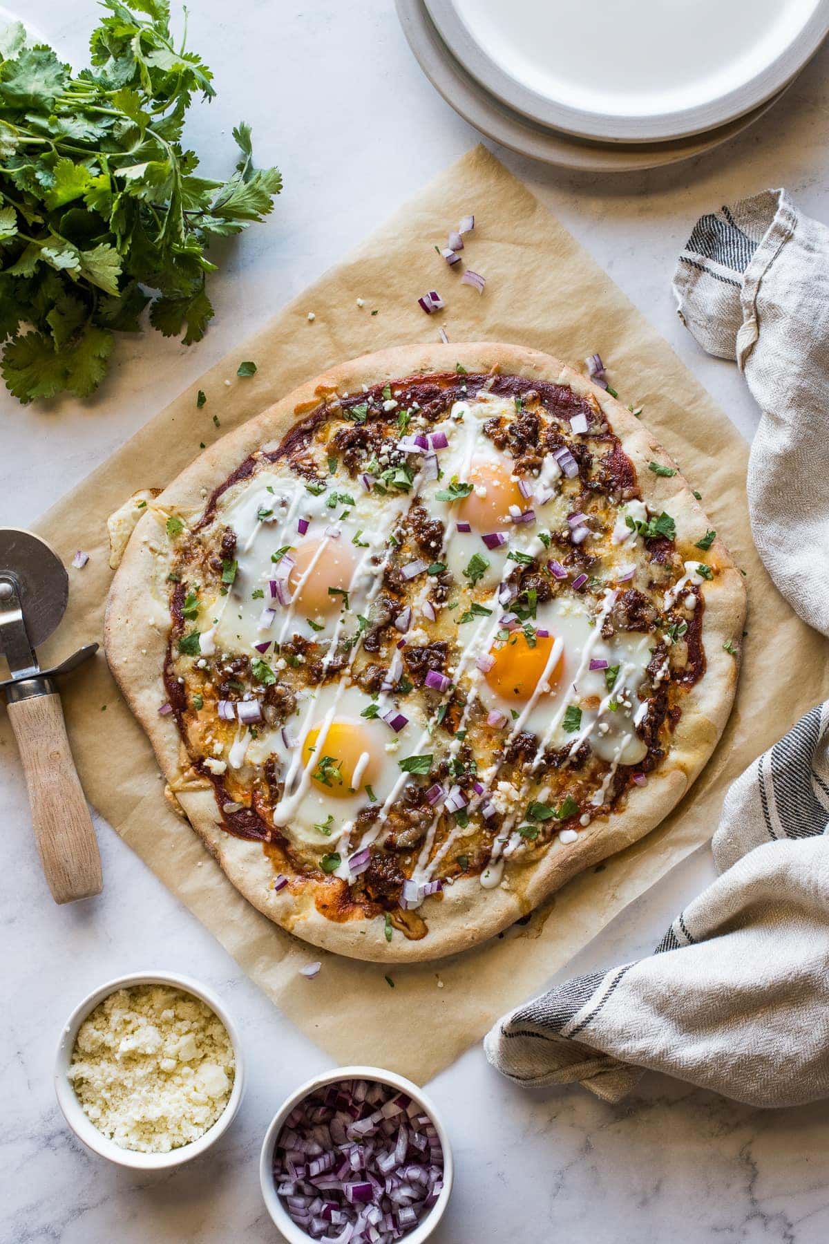 Mexican Breakfast Pizza topped with sour cream, cilantro, and onions.