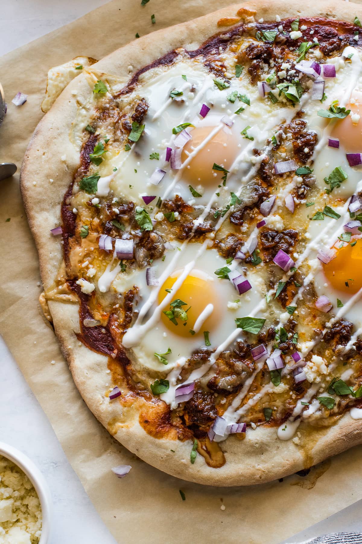 Breakfast pizza topped with sour cream, onions, and cilantro.