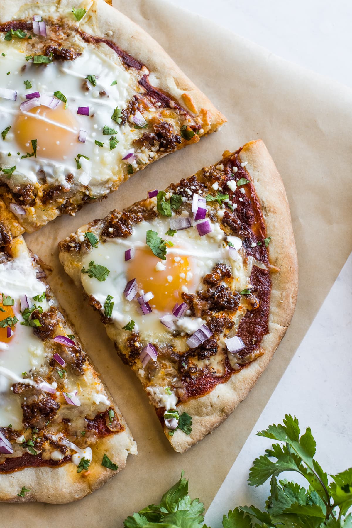 A slice of breakfast pizza topped with a baked egg.