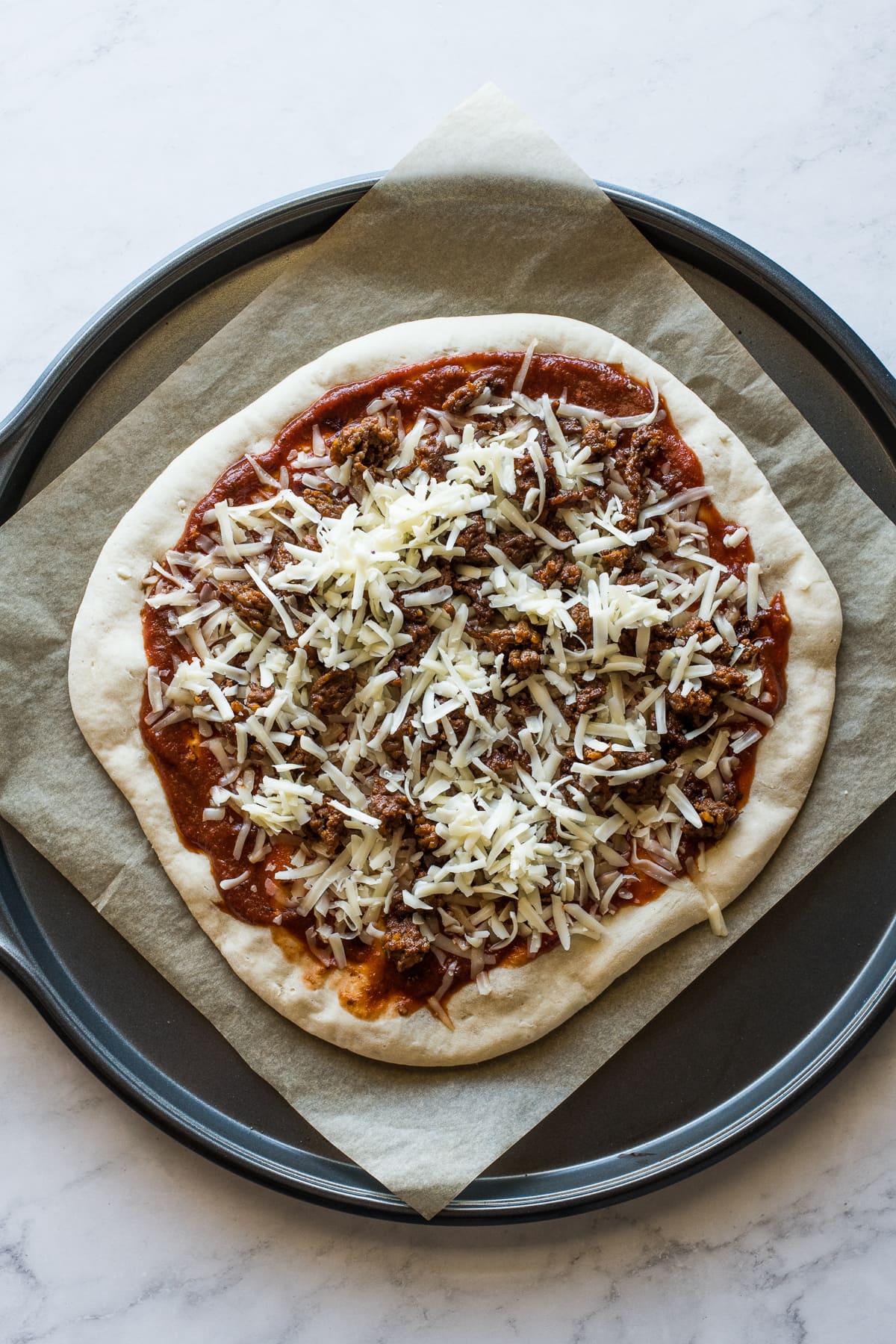 Chipotle tomato sauce on a pizza crust topped with cheese and chorizo.