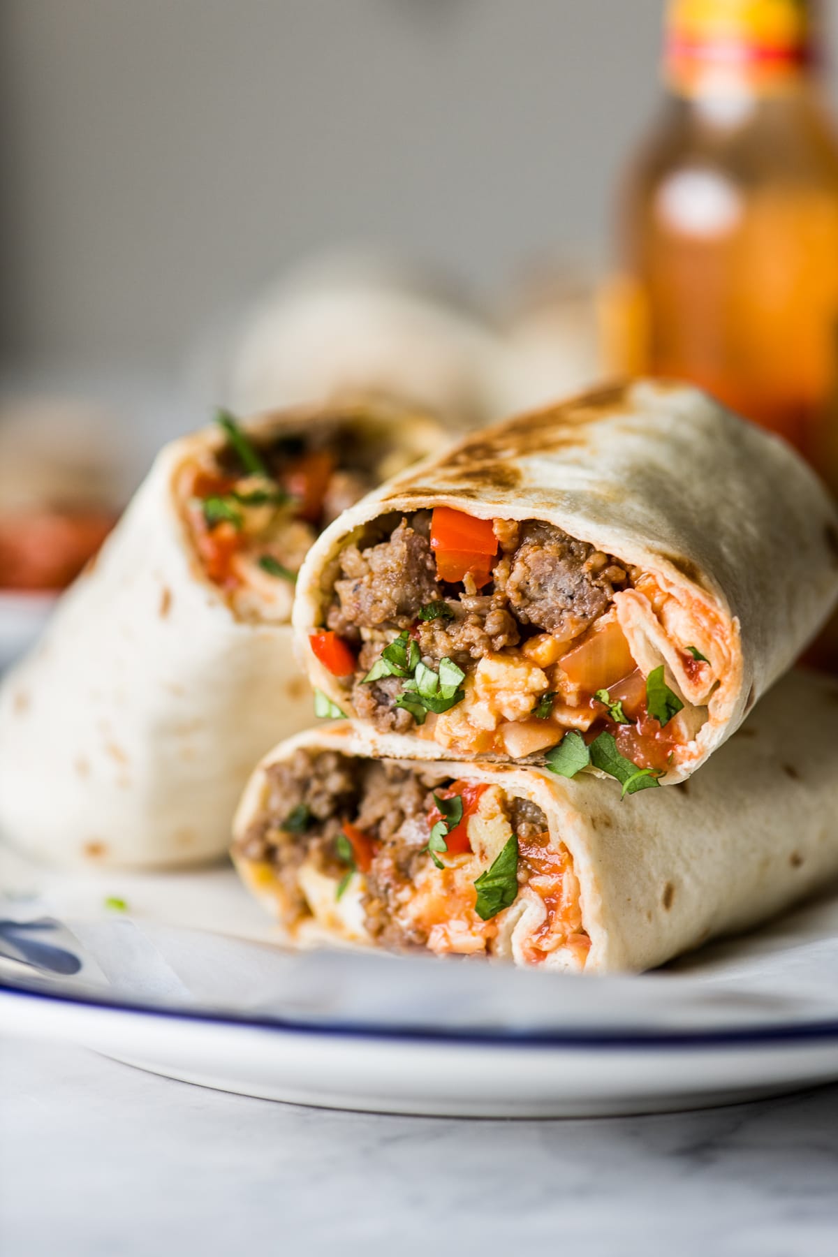 Breakfast burritos on a plate stacked on top of one another.