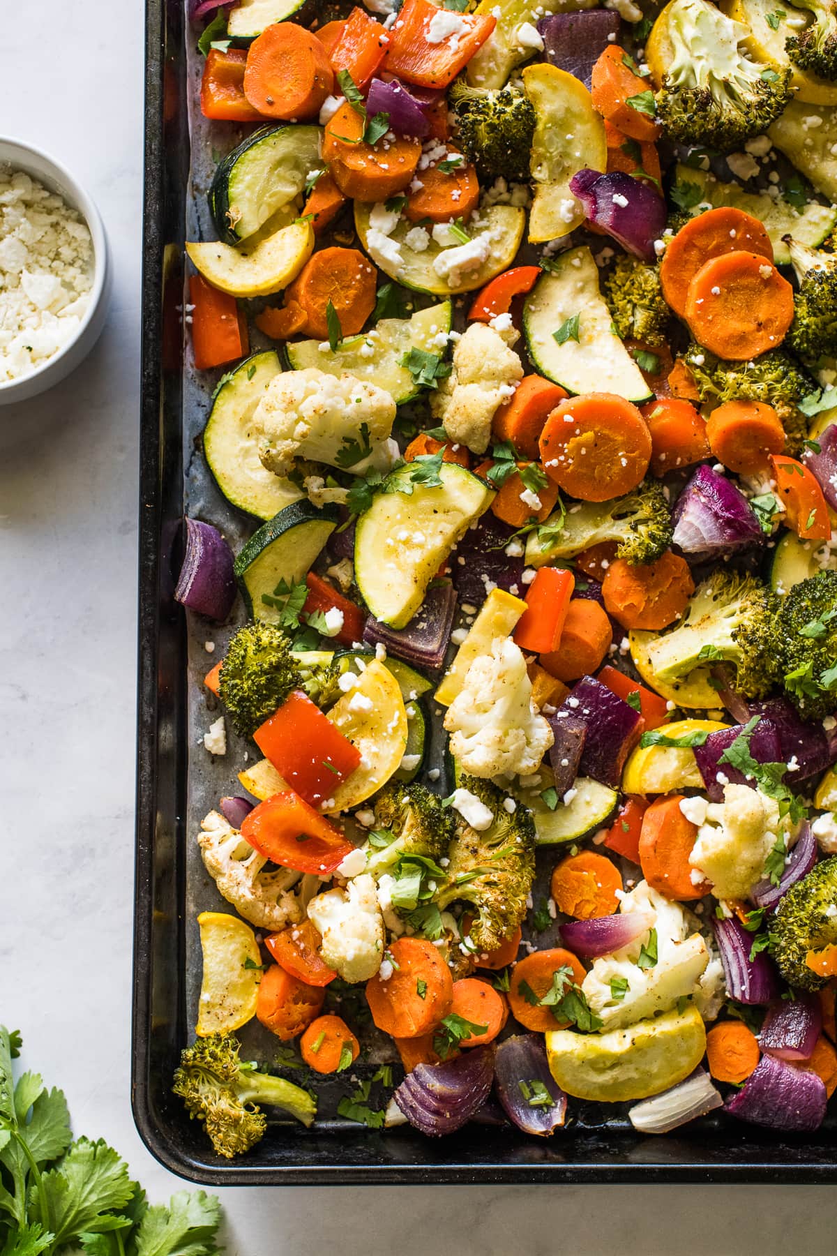 Mexican vegetables roasted on a sheet pan topped with lime juice, cotija cheese, and cilantro.