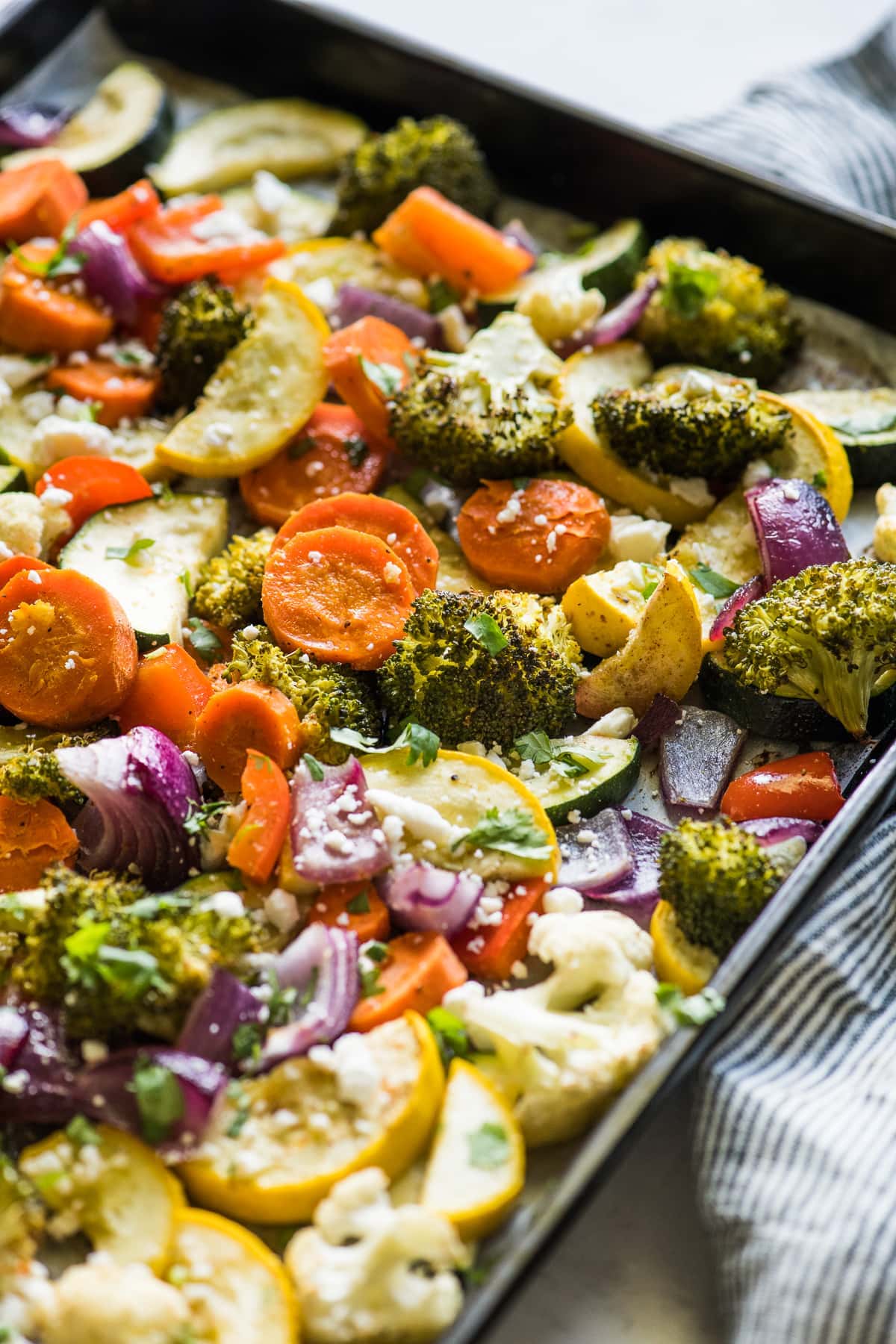 Roasted vegetables on a sheet pan topped with cilantro and cotija cheese.