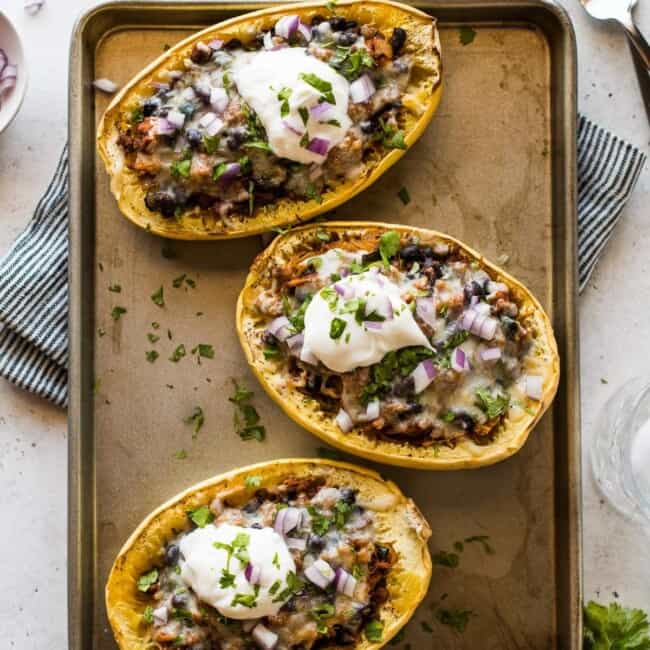Taco stuffed spaghetti squash topped with cilantro, red onions, and sour cream.