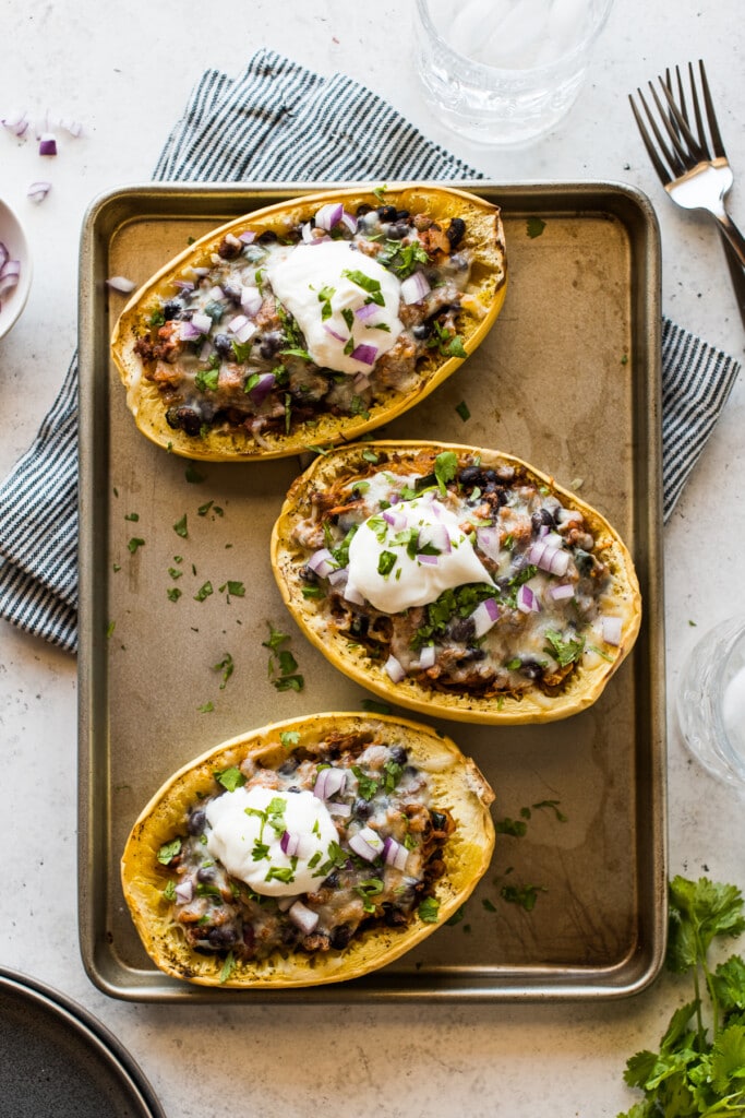 Taco stuffed spaghetti squash topped with cilantro, red onions, and sour cream.