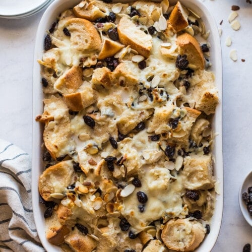 Capirotada (or Mexican Bread Pudding) in a baking dish topped with raisins and cheese.