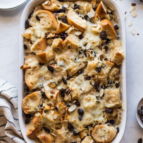 Capirotada (or Mexican Bread Pudding) in a baking dish topped with raisins and cheese.