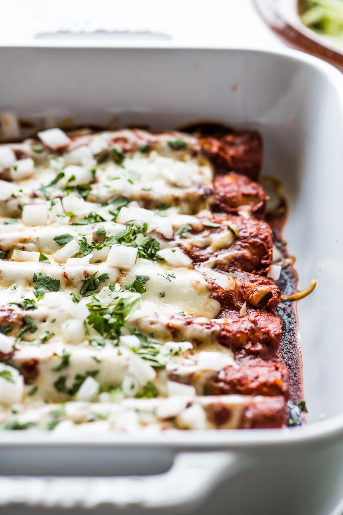 Cheese enchiladas topped with melted cheese, cilantro, and onions.
