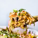 A spoonful of chicken enchilada casserole about to be served onto a plate.