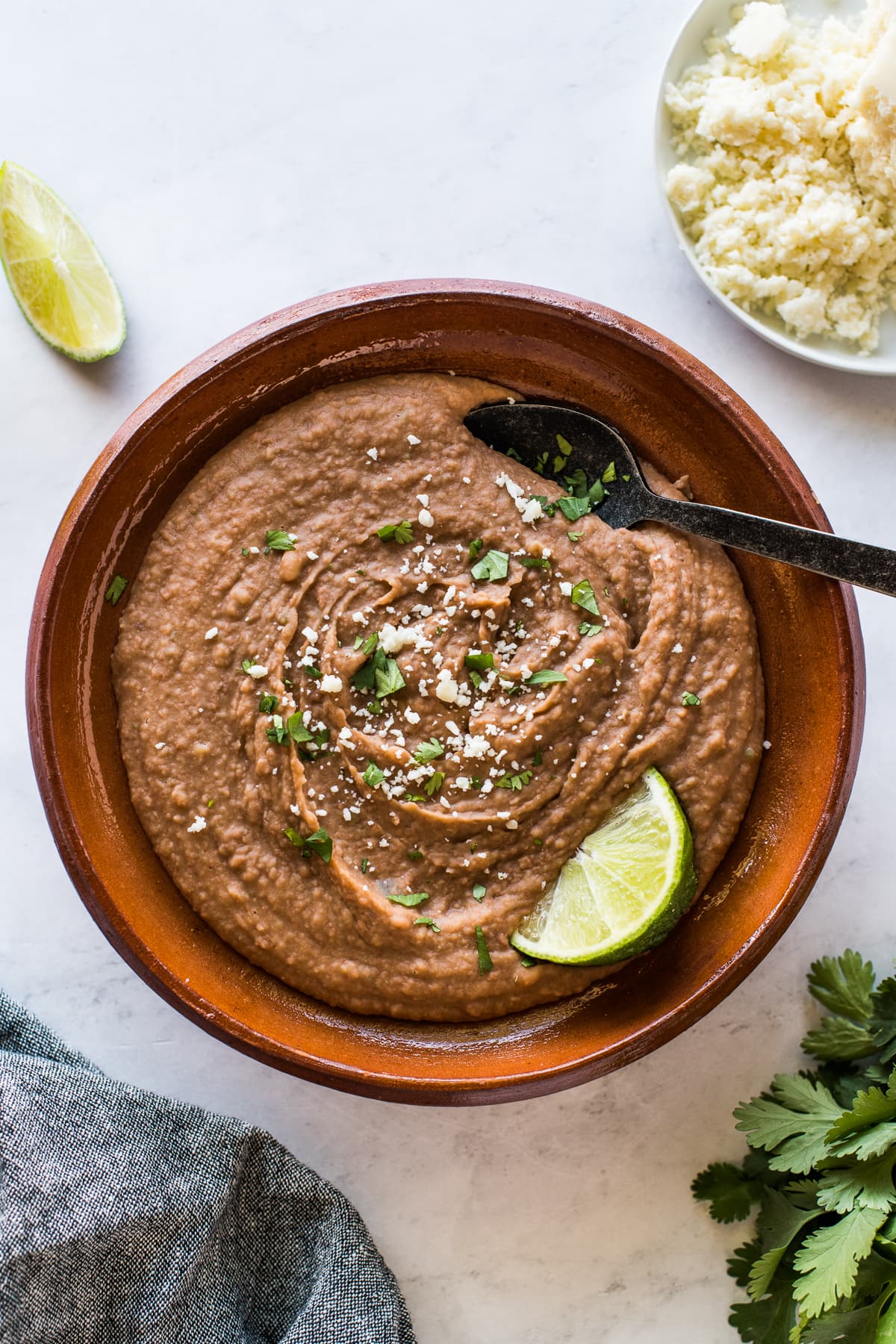 Instant Pot refried beans in a bowl topped with cilantro and cotija cheese.