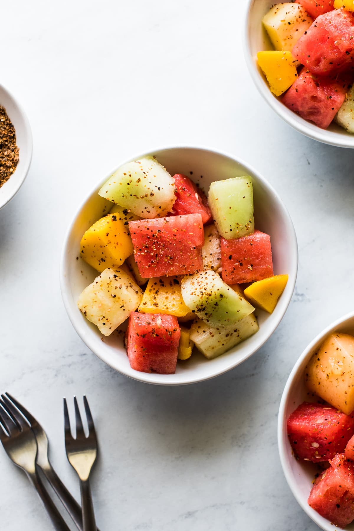 Mexican fruit salad in a bowl sprinkled with Tajin seasoning.