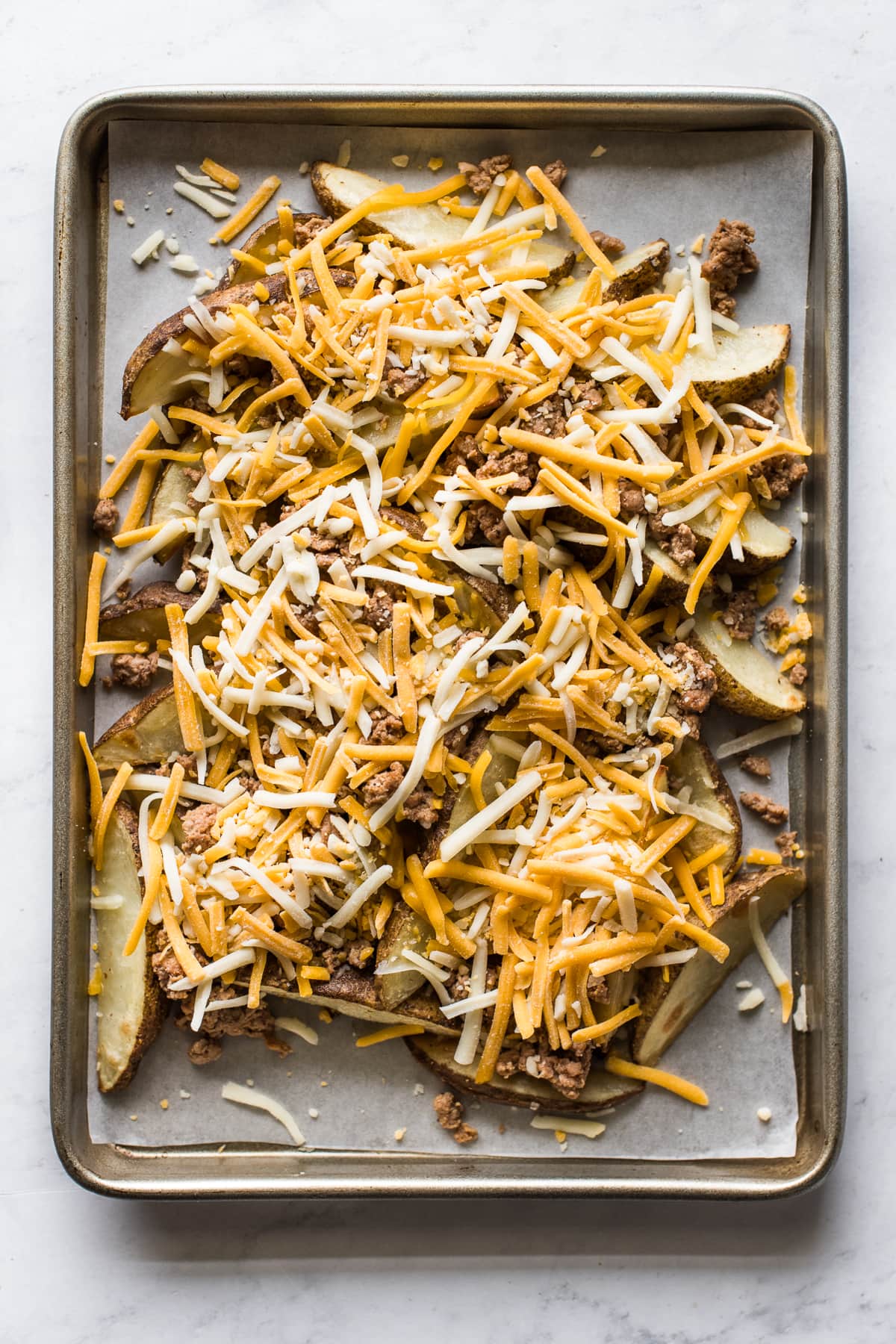 Baked potato wedges topped with shredded cheese.