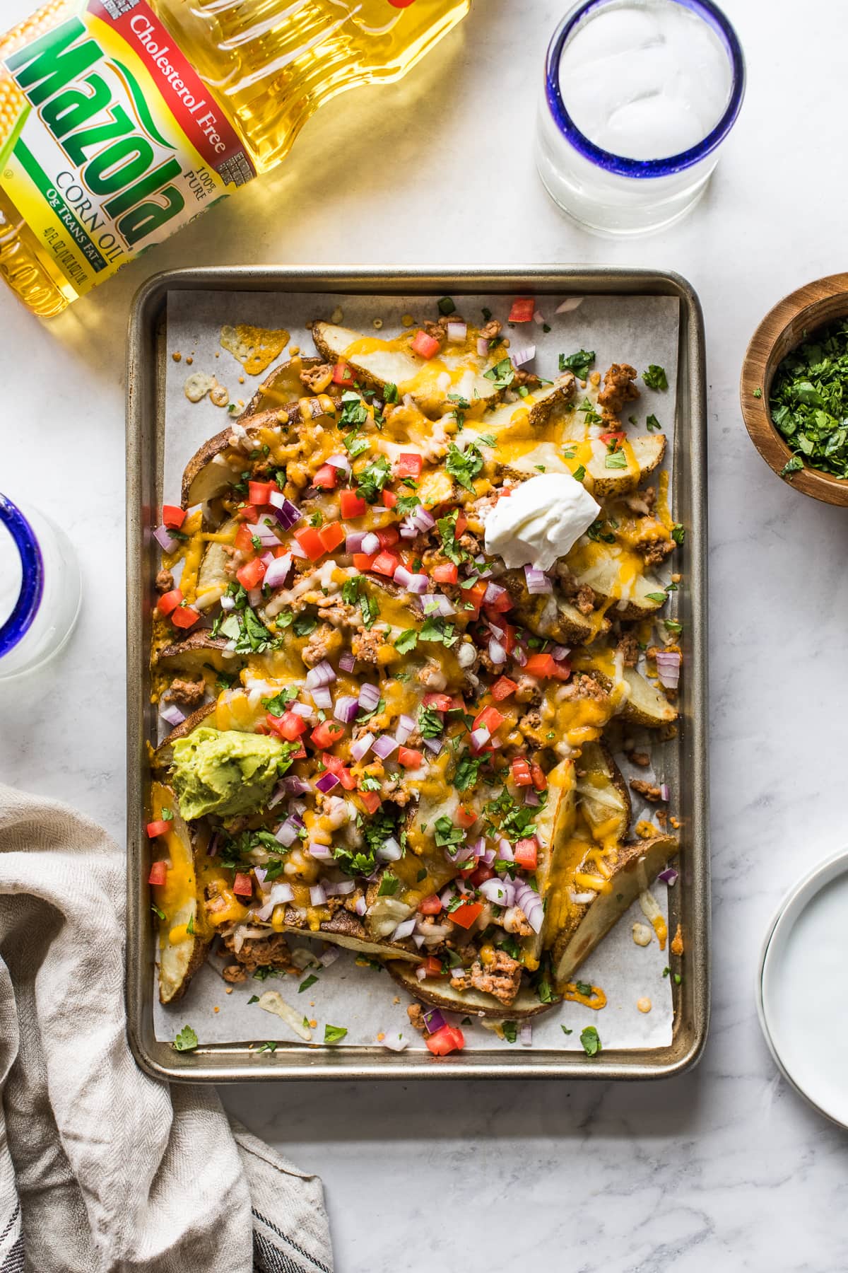 Baked potato wedges topped with melted cheese on a baking sheet.