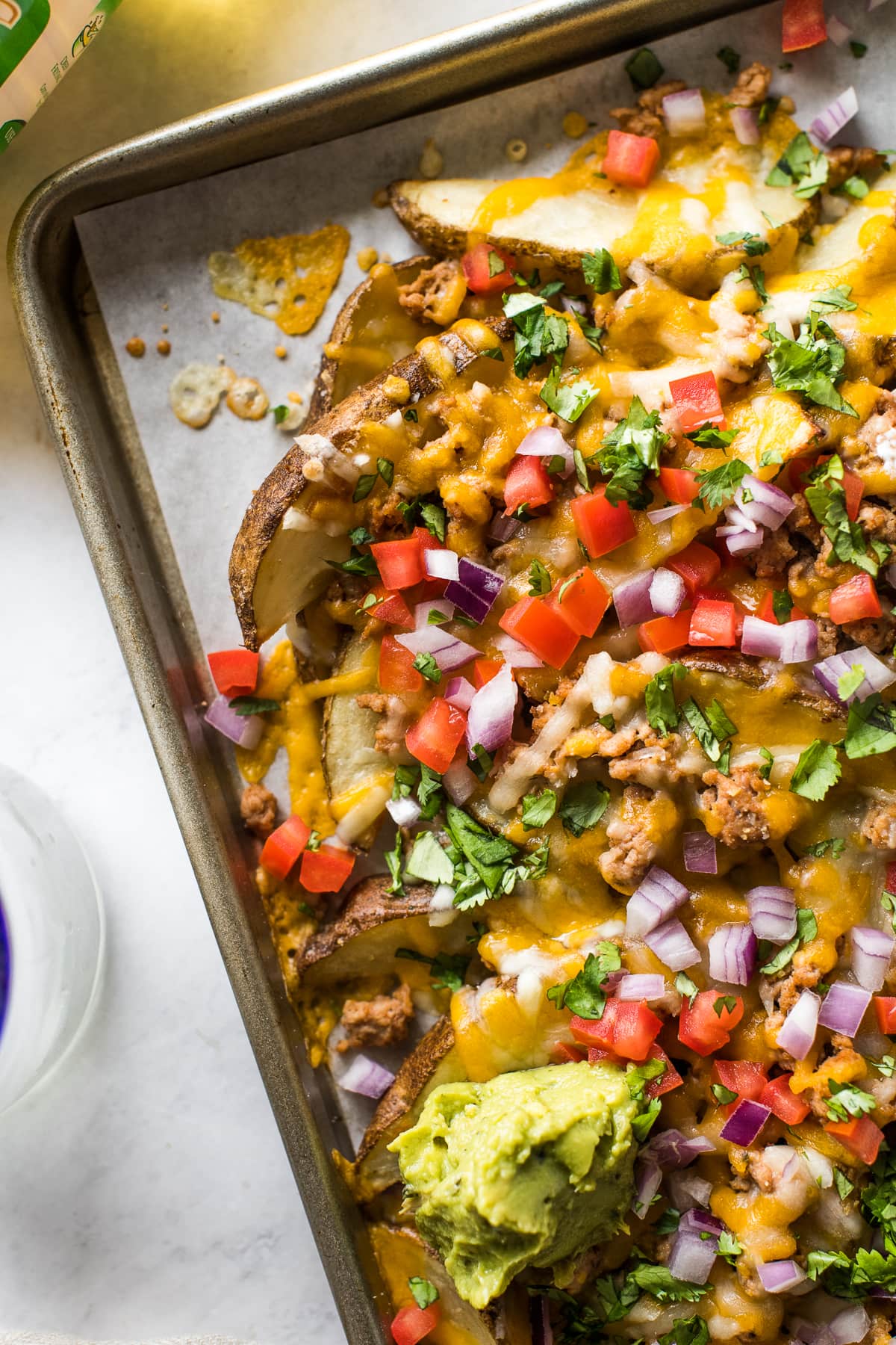 Loaded potato wedges topped with melted cheese, tomatoes, onions, cilantro, and guacamole.