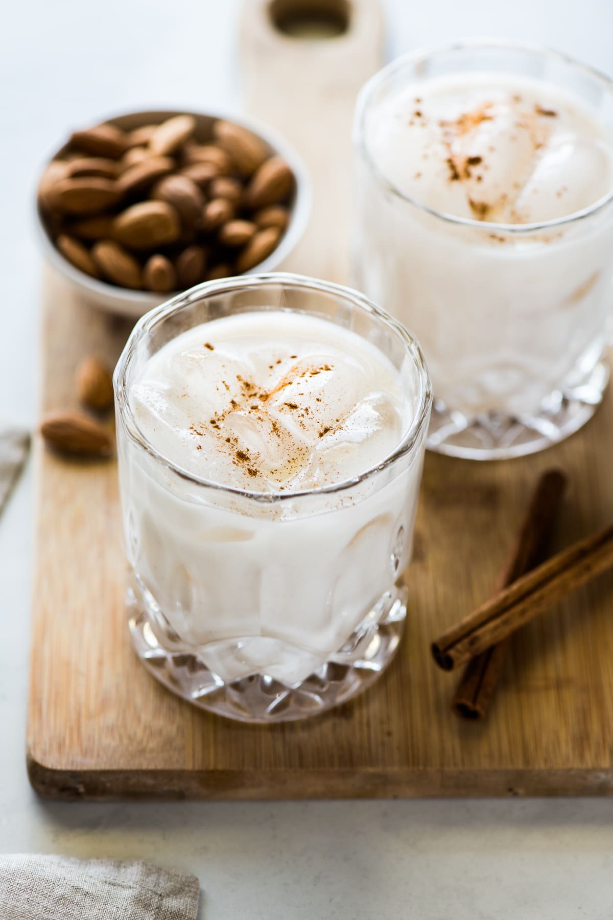 A glass of horchata filled with ice and garnished with a touch of ground cinnamon.