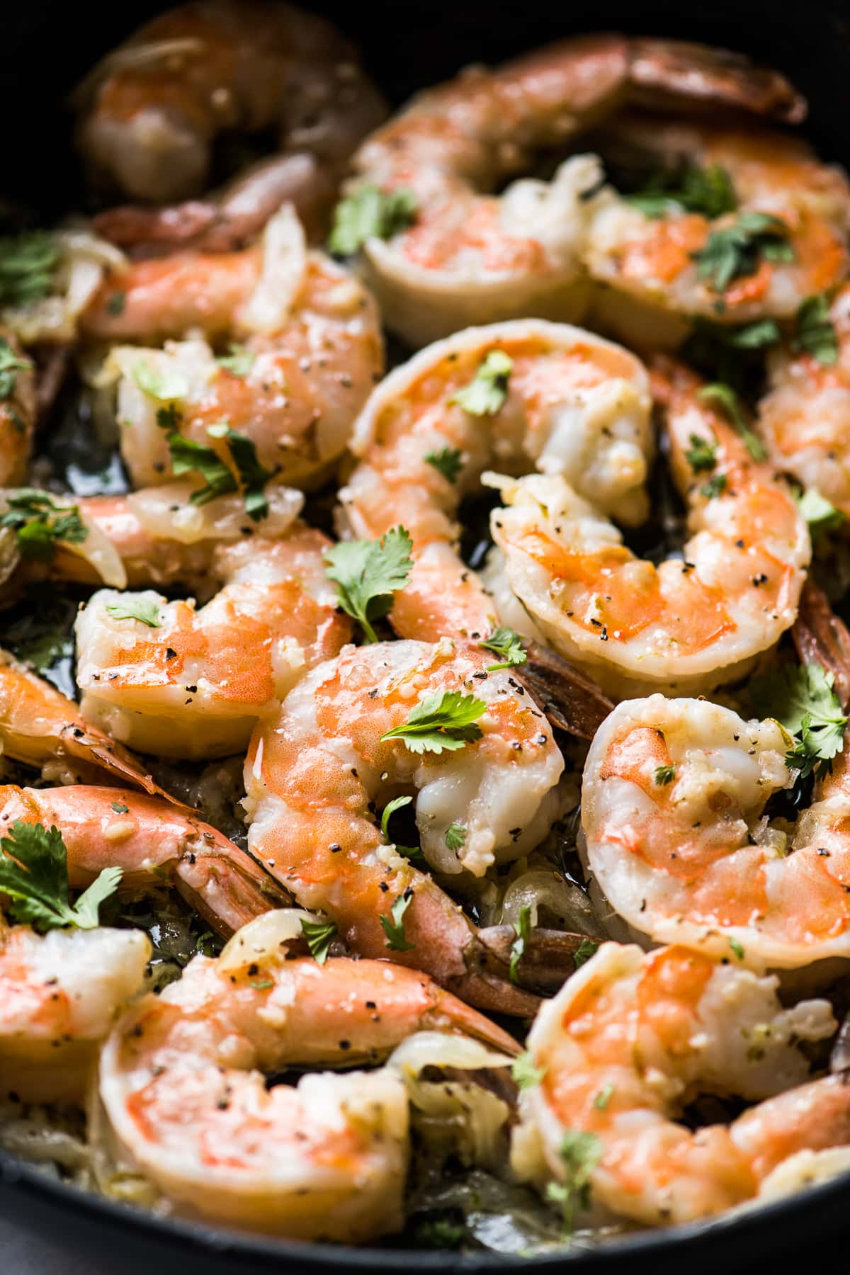 Camarones al Mojo de Ajo in a skillet garnished with cilantro in garlic butter sauce.