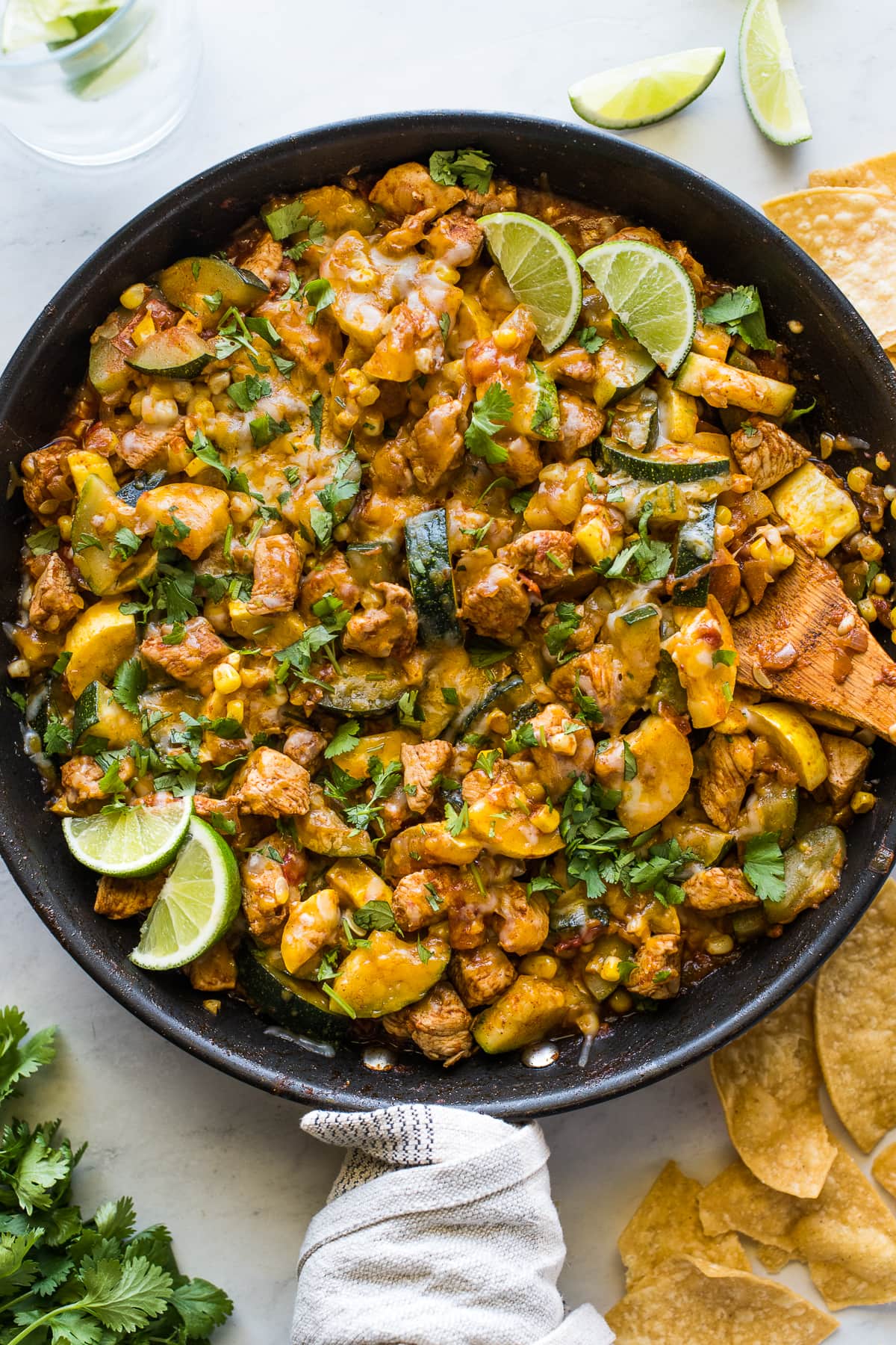 Chicken and Squash in a skillet with cilantro and limes.