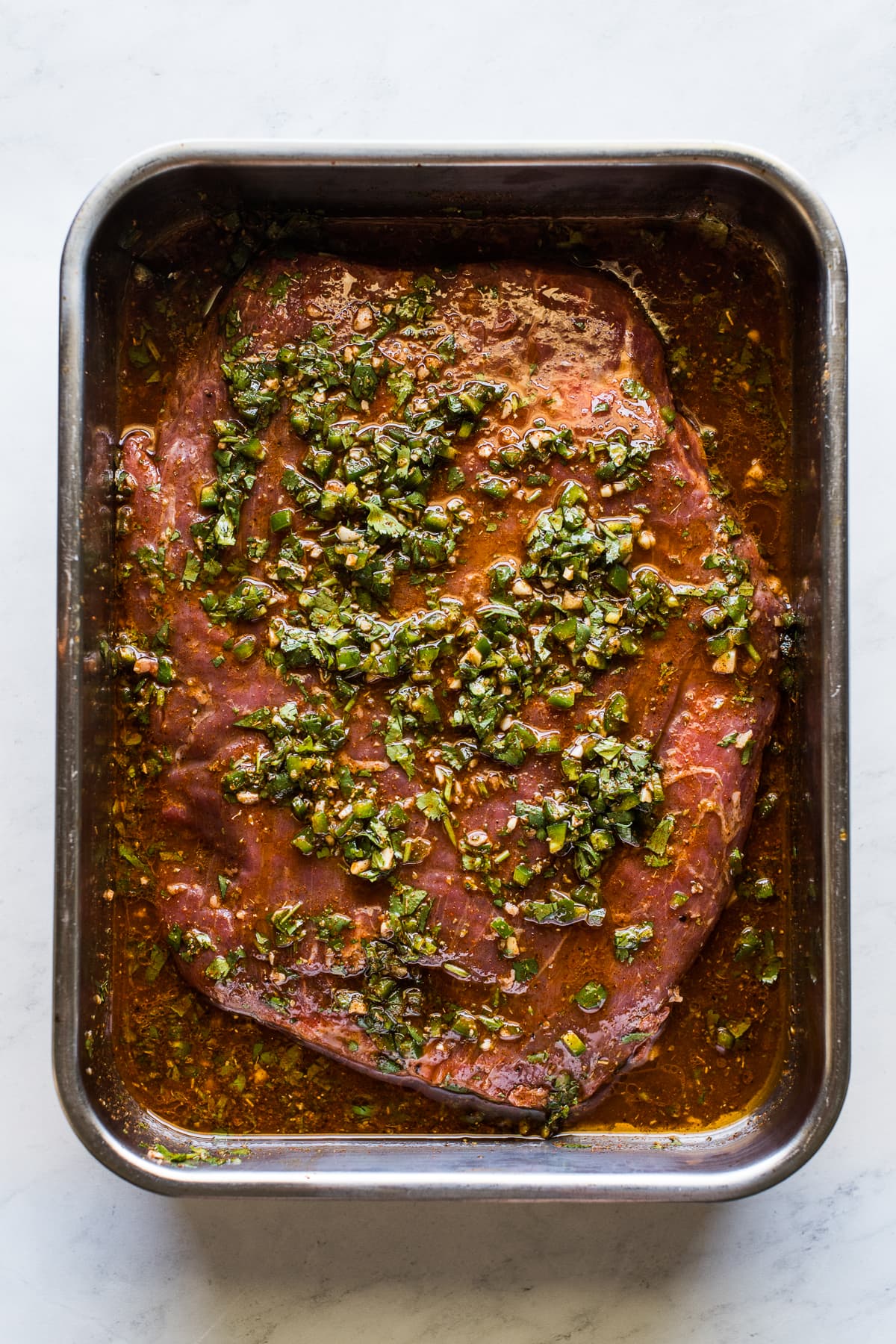 Carne asada marinating in a pan.