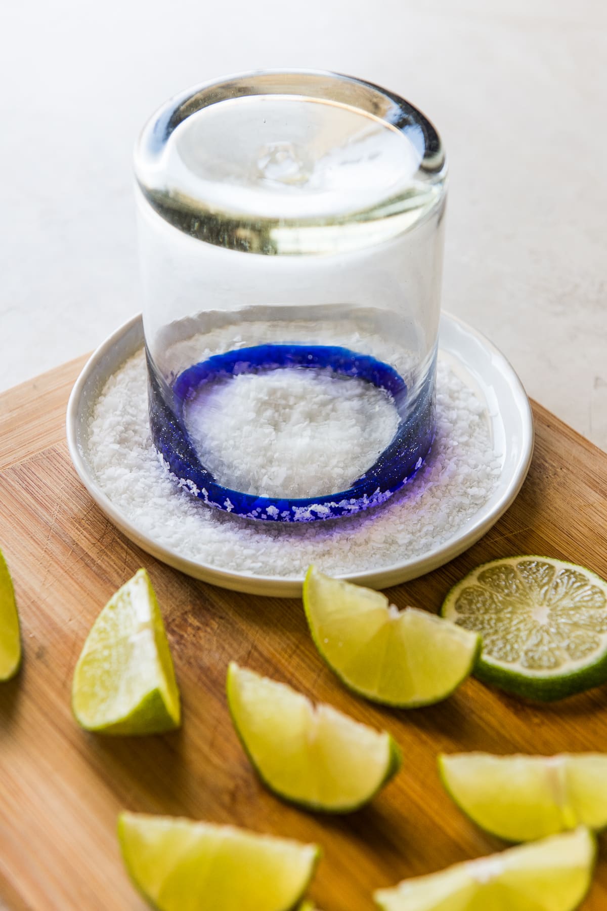A blue-rimmed margarita glass being dipped in salt and lime juice.