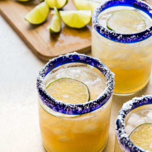 A classic margarita recipe in an iced glass garnished with fresh lime and a salted rim.
