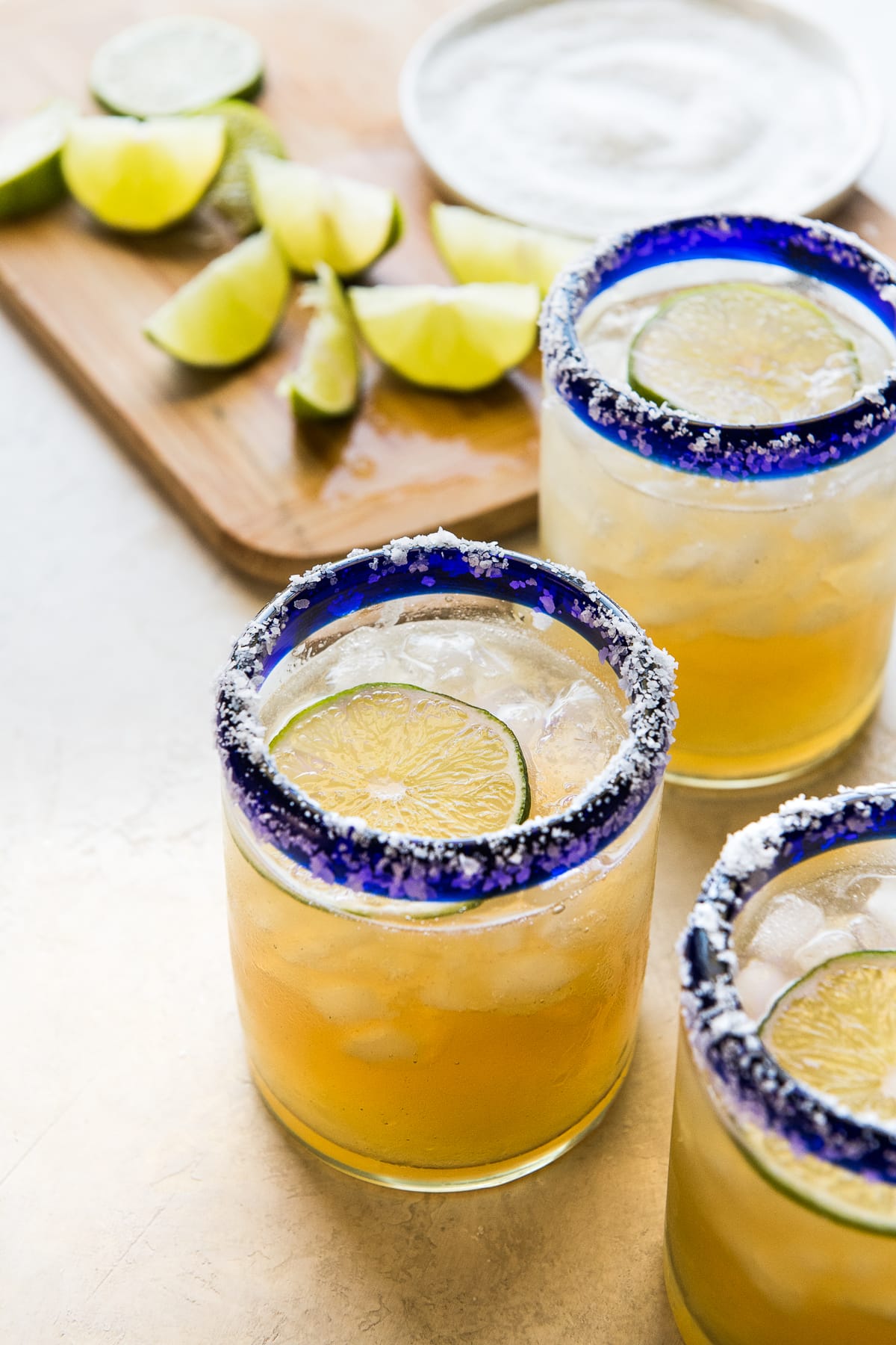 A classic margarita recipe in an iced glass garnished with fresh lime and a salted rim.