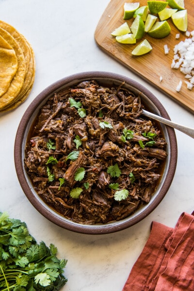 Shredded Instant Pot barbacoa in a large serving bowl garnished with fresh cilantro.