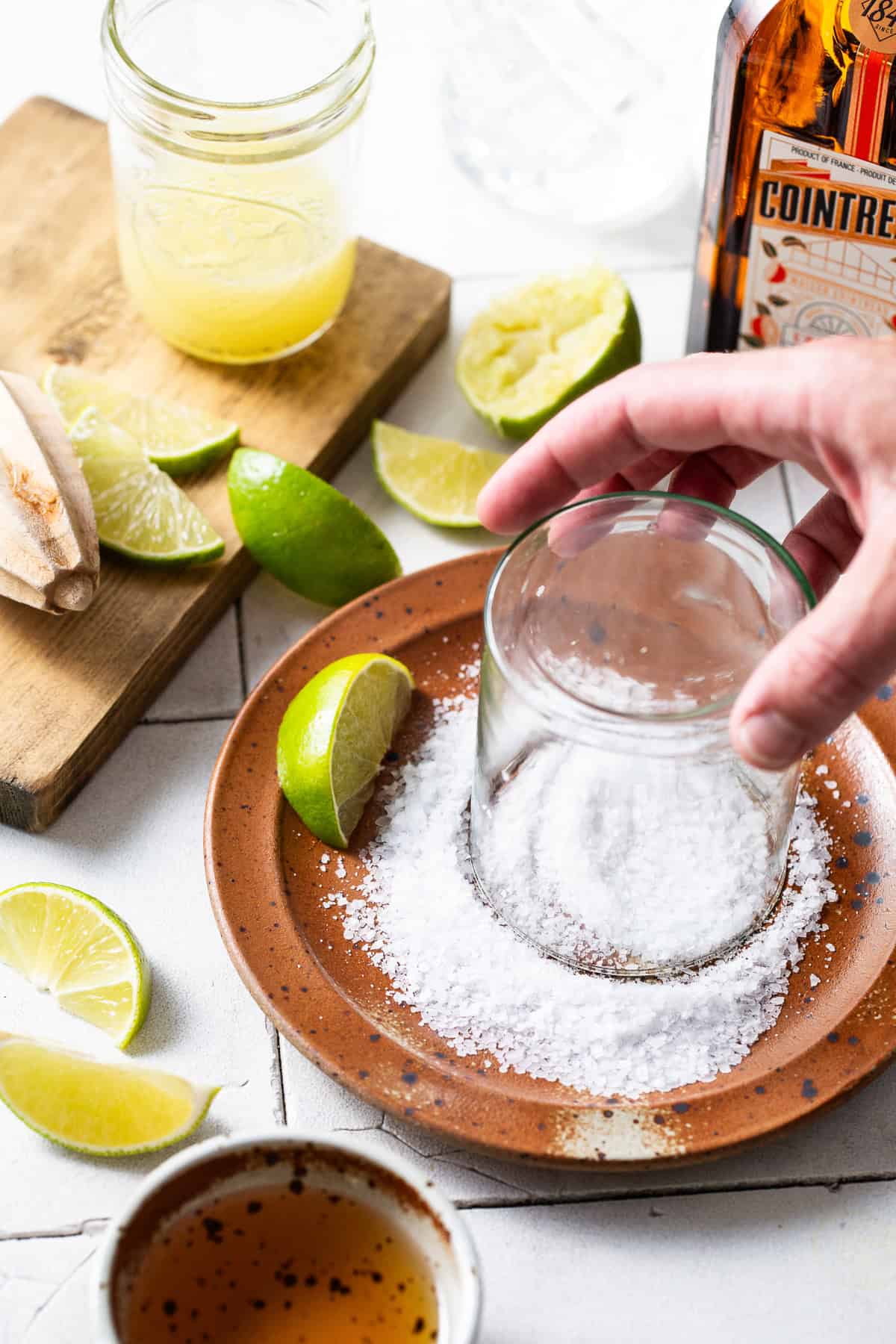 The rim of a glass being dipped in coarse salt before pouring in the margarita.