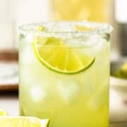 Classic margarita recipe in a rocks glass with a salted rim and lime wedge