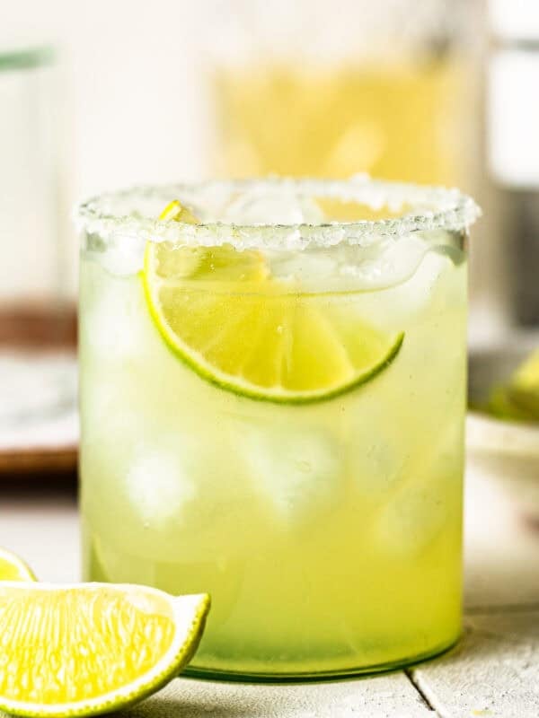 Classic margarita recipe in a rocks glass with a salted rim and lime wedge