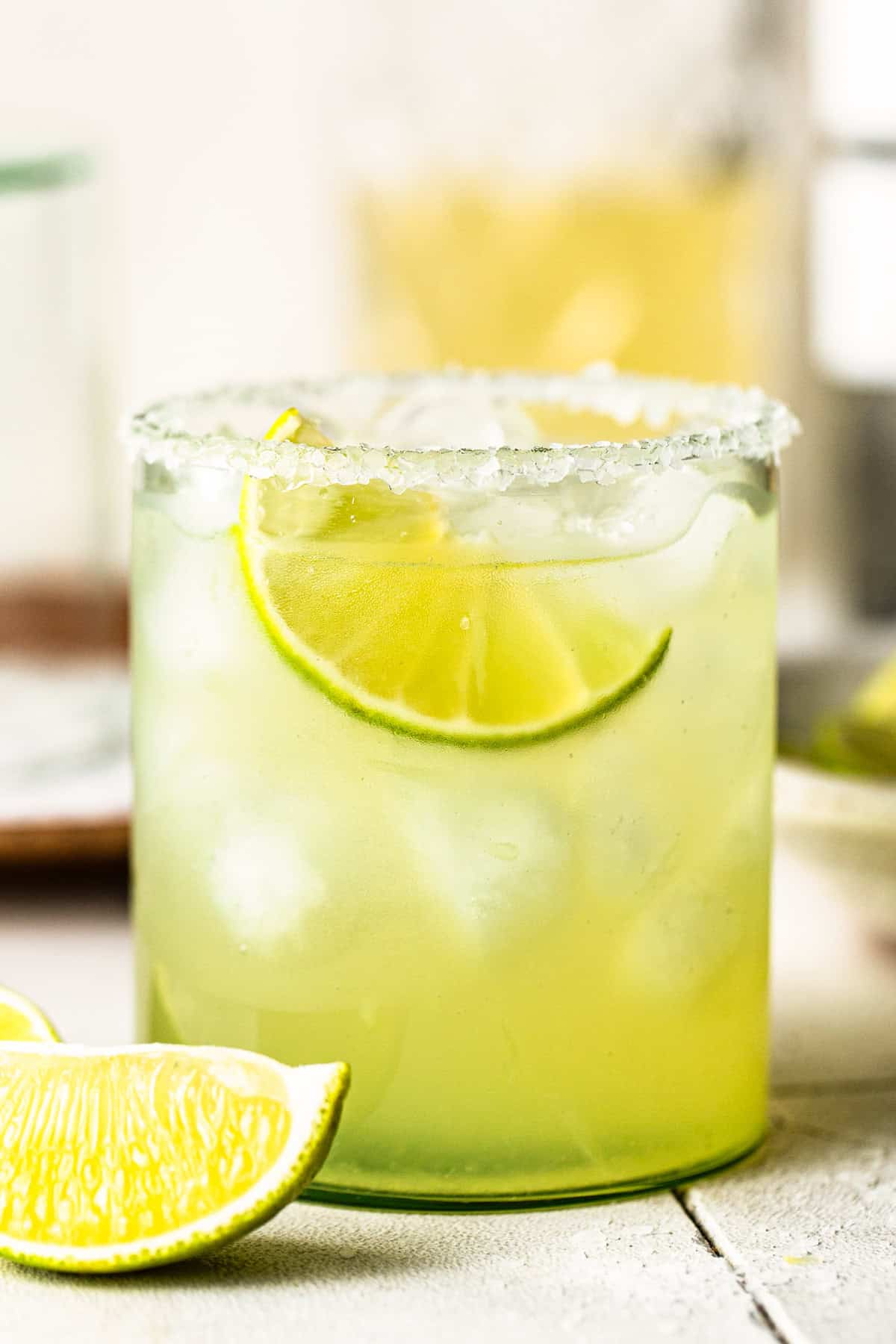 Classic margarita recipe in a rocks glass with a salted rim and lime wedge