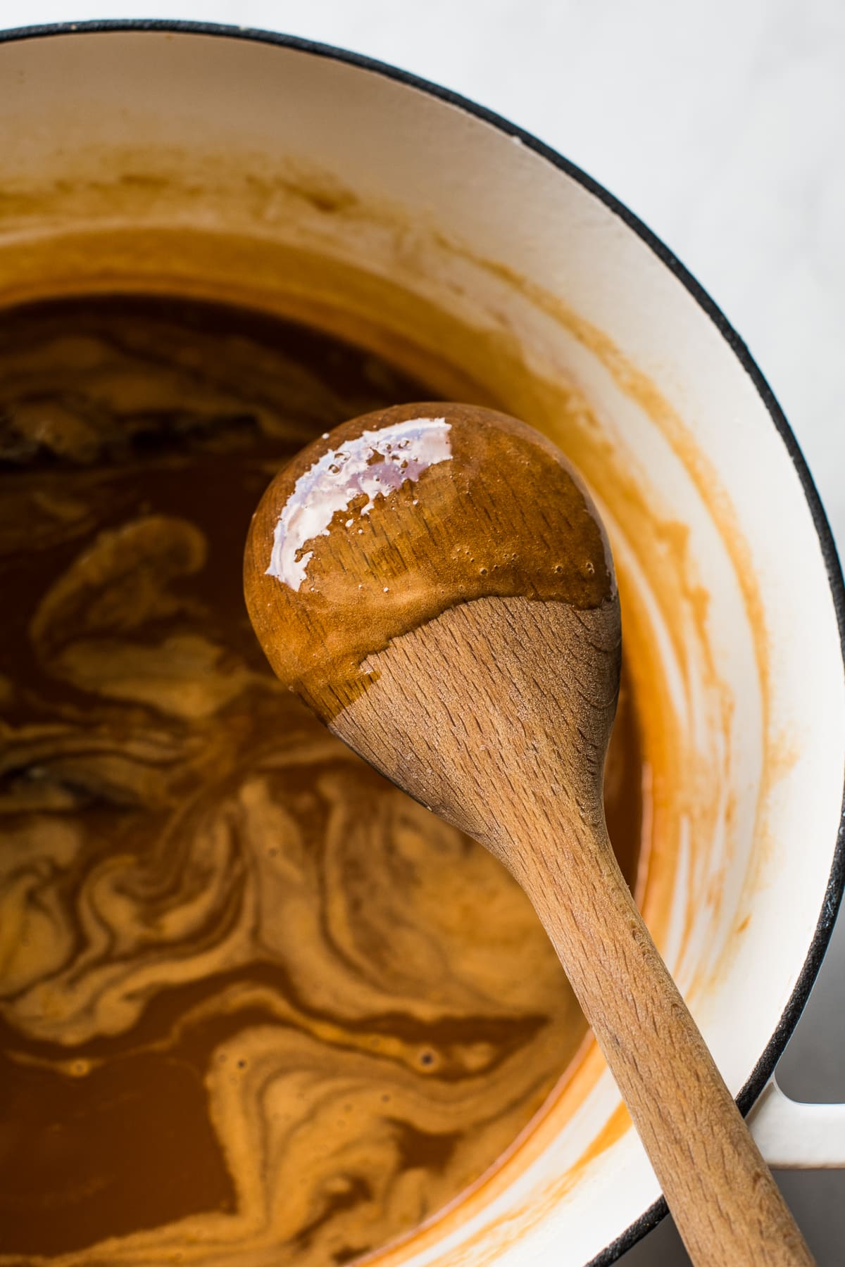 Cajeta sticking to the back of a wooden spoon to show its thickness and consistency.