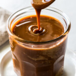 Cajeta pouring from a spoon into a glass jar.