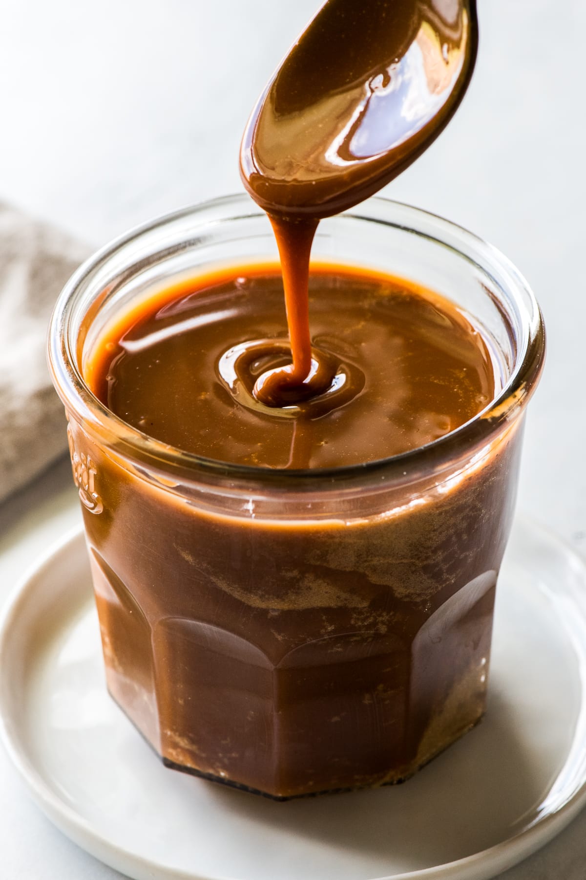 Cajeta pouring from a spoon into a glass jar.