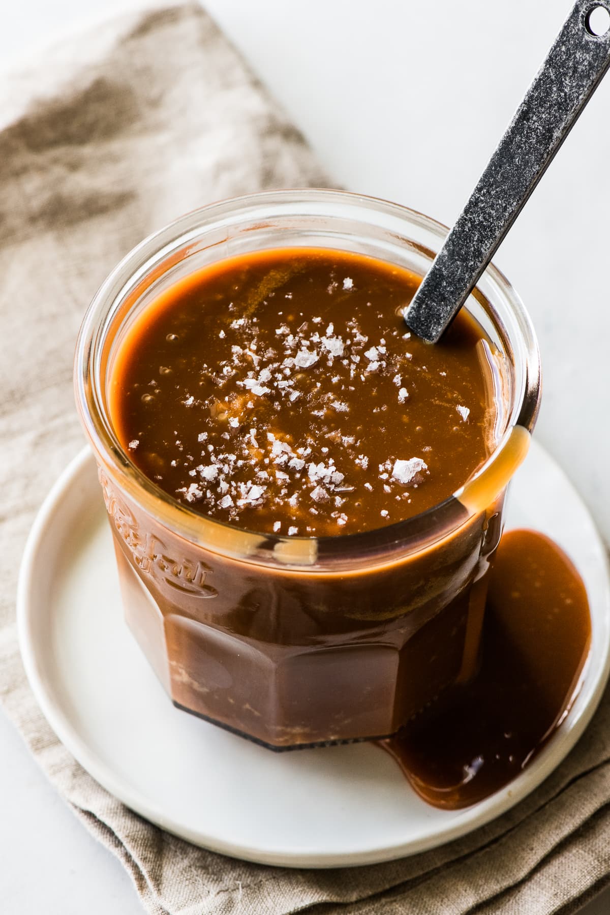 Cajeta (Mexican caramel) in a glass jar garnished with flaky sea salt.