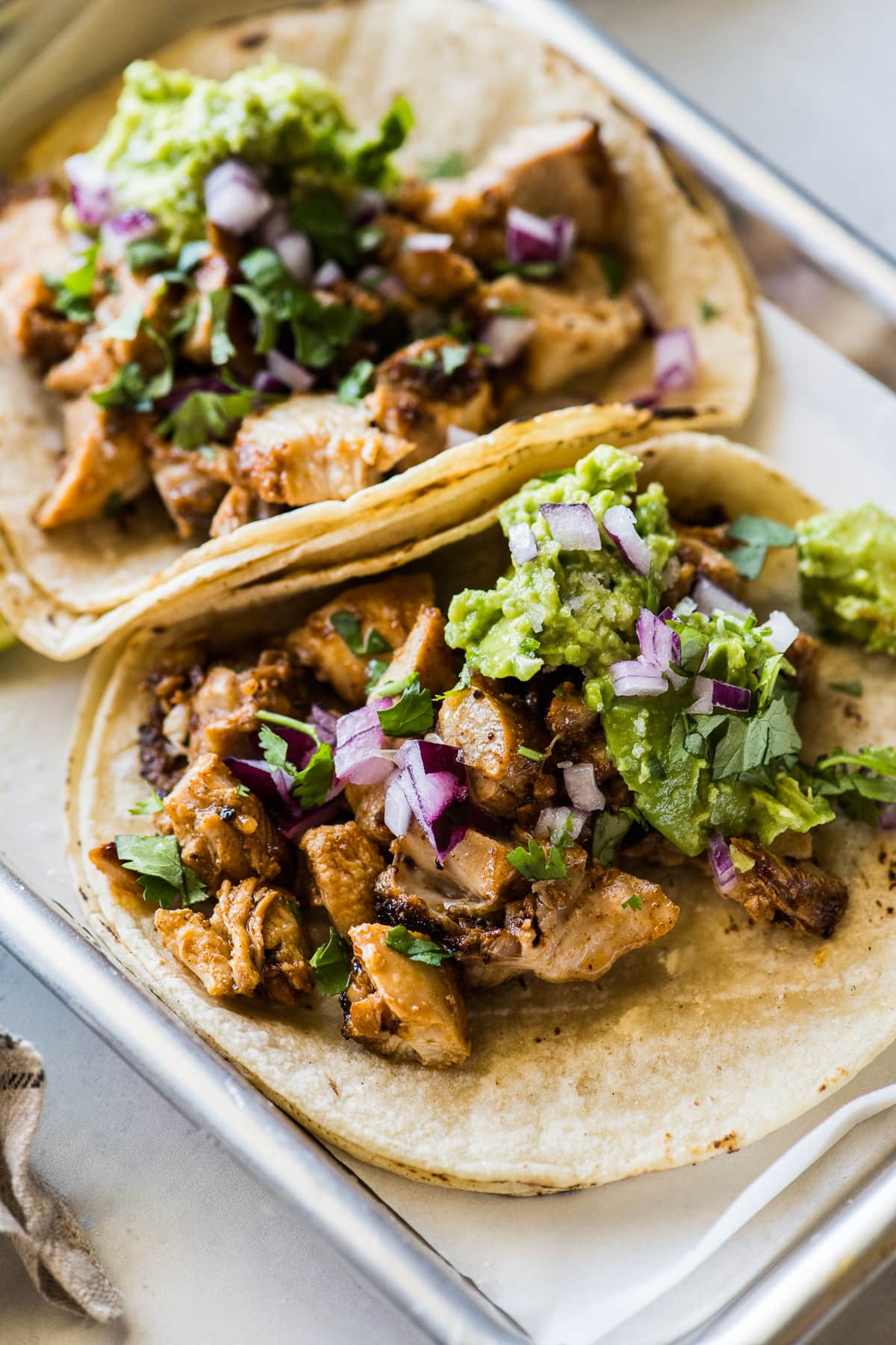 The best chicken tacos recipe on warm corn tortillas topped with avocado, red onion, cilantro and lime juice.
