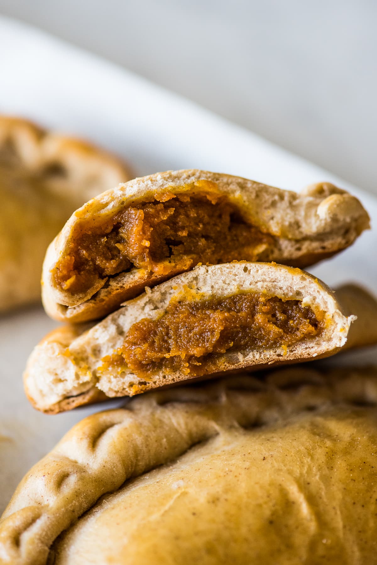 Pumpkin Empanadas cut in half with pumpkin filling exposed.